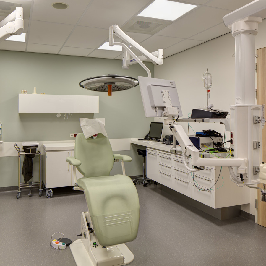 Hier is een grijze tandarts stoel te zien in een kamer.
