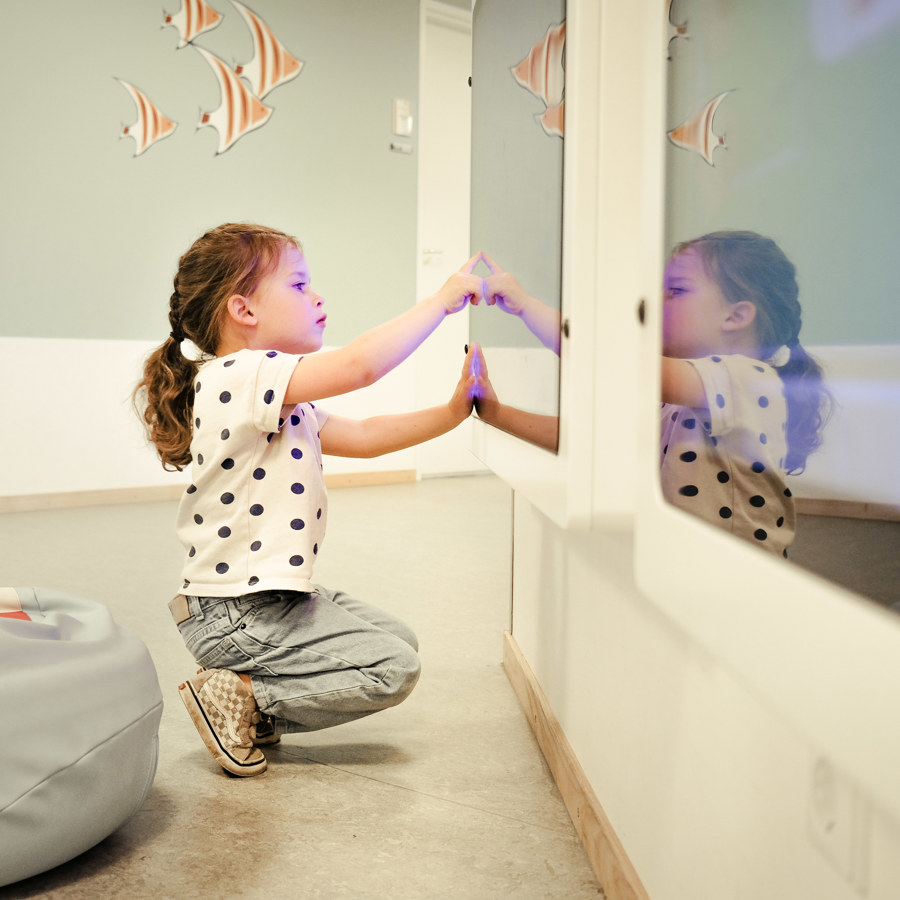 Een kind dat speelt op een scherm met op de achtergrond getekende vissen op de muur.