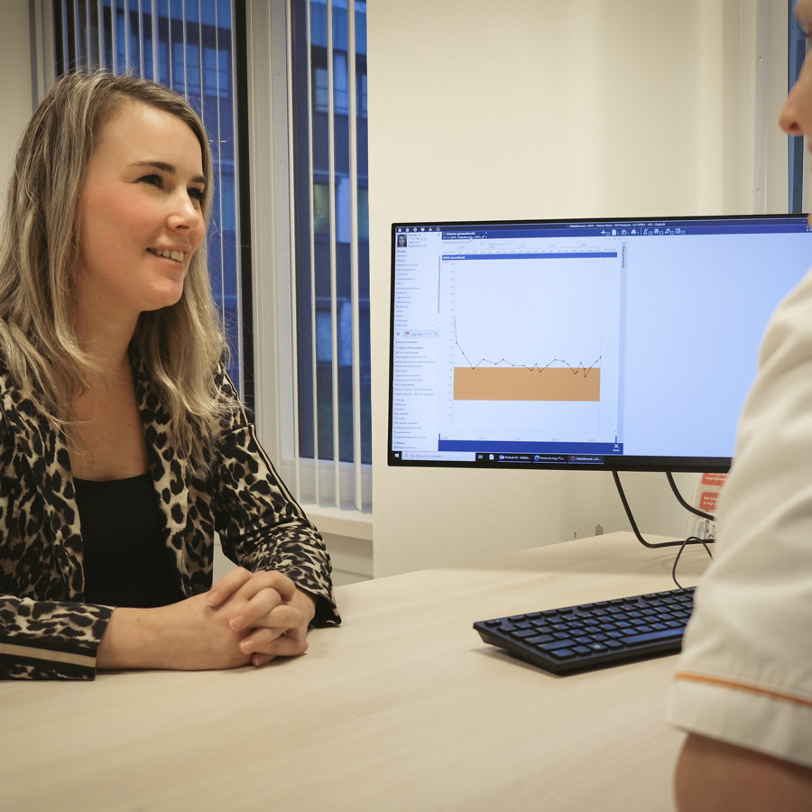 patiente in gesprek met zorgverlener in spreekkamer bij een beeldscherm