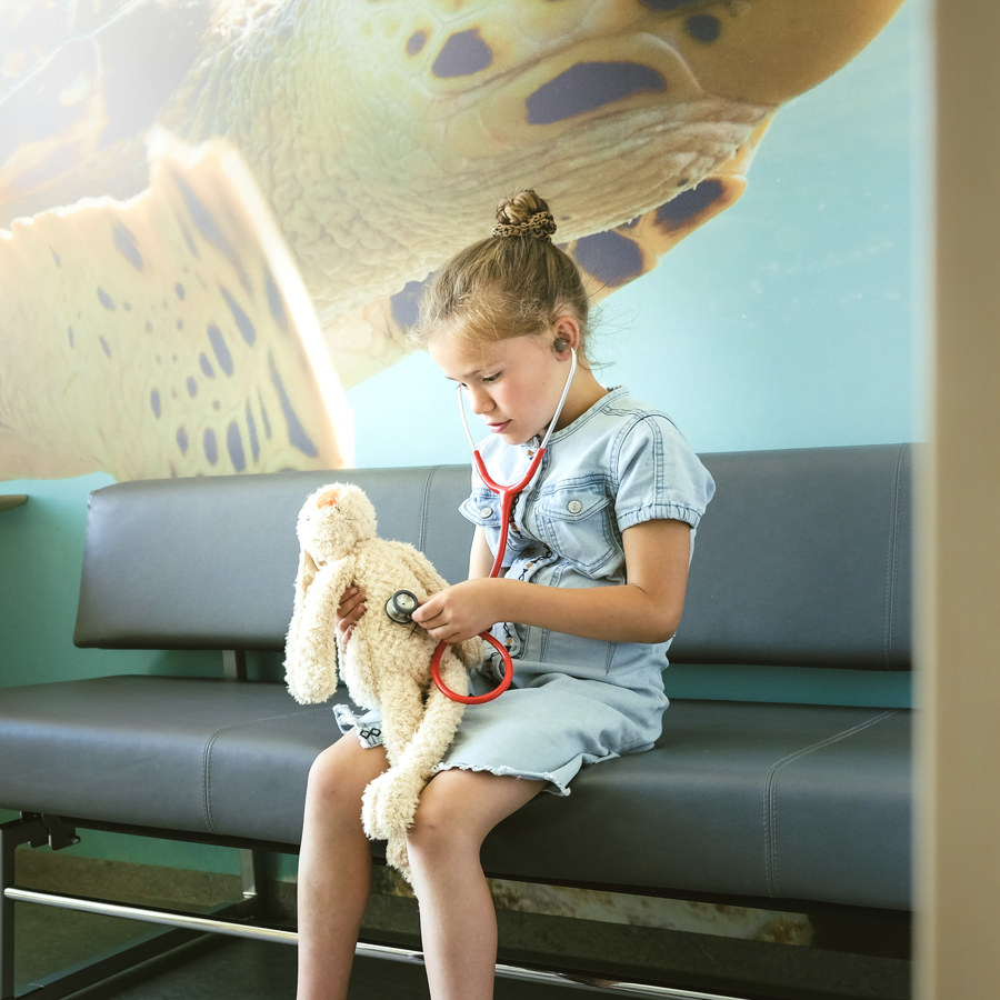 Meisje met konijn en stethoscoop op een bankje bij Kindergeneeskunde VieCuri