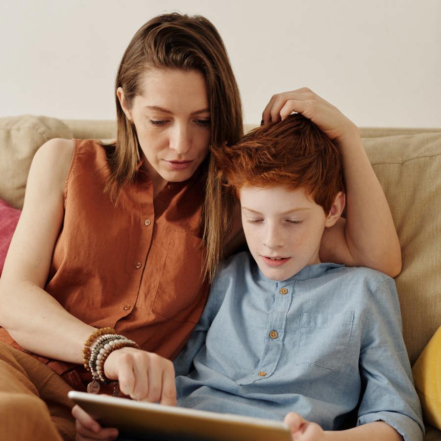 Moeder en zoon op tablet op de bank