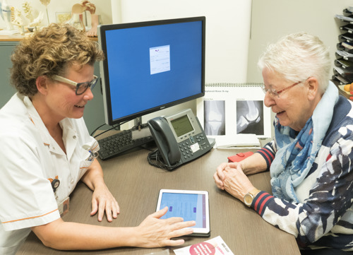 Orthopedieconsulente legt patient de patient journey app uit.