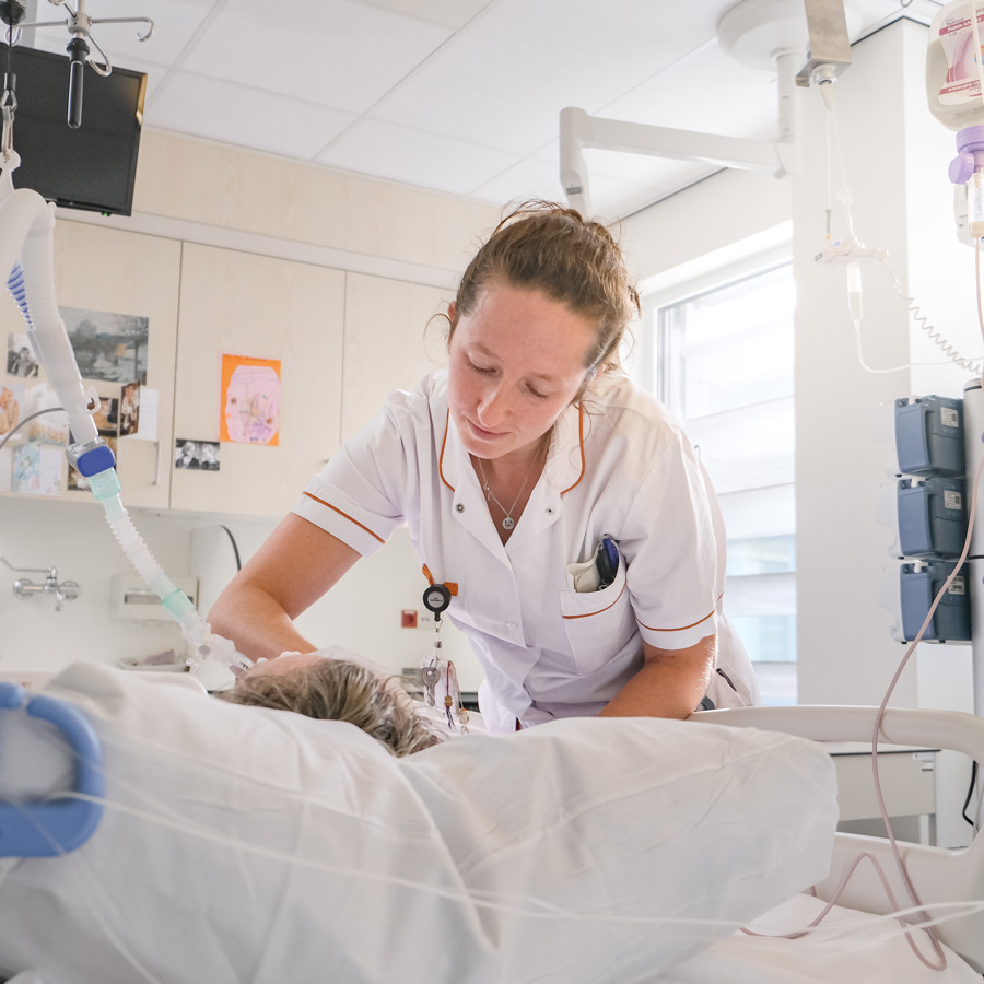 Een intensive care verpleegkundige verzorgt een patiënt in bed